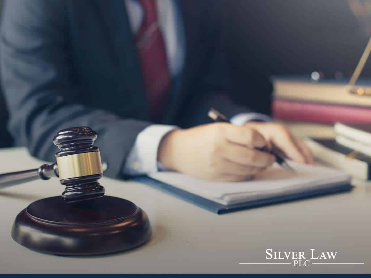 A legal professional writes notes next to a judge's gavel on a desk, symbolizing BOI Reporting activities within a law firm setting